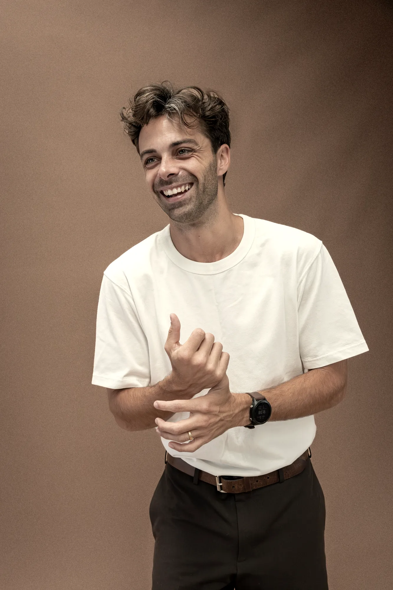 Jacob laughing, in a white T-shirt against a brown backdrop