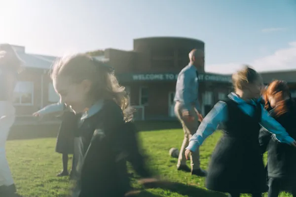 Students playing with teacher on school grounds